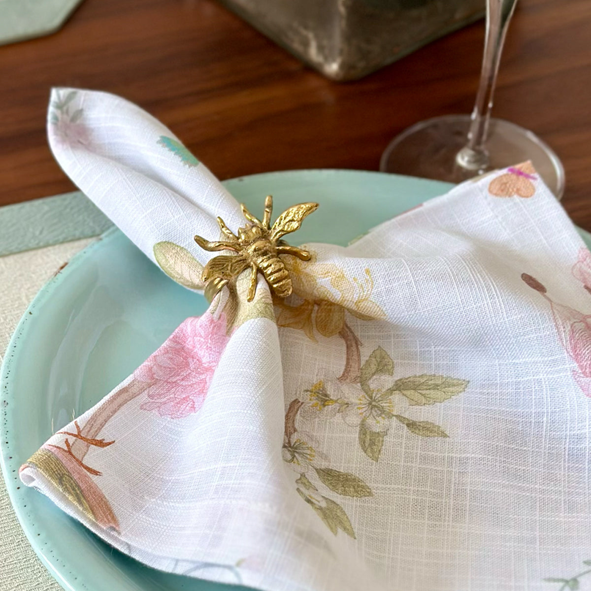 Bee gold napkin ring on a white floral napkin
