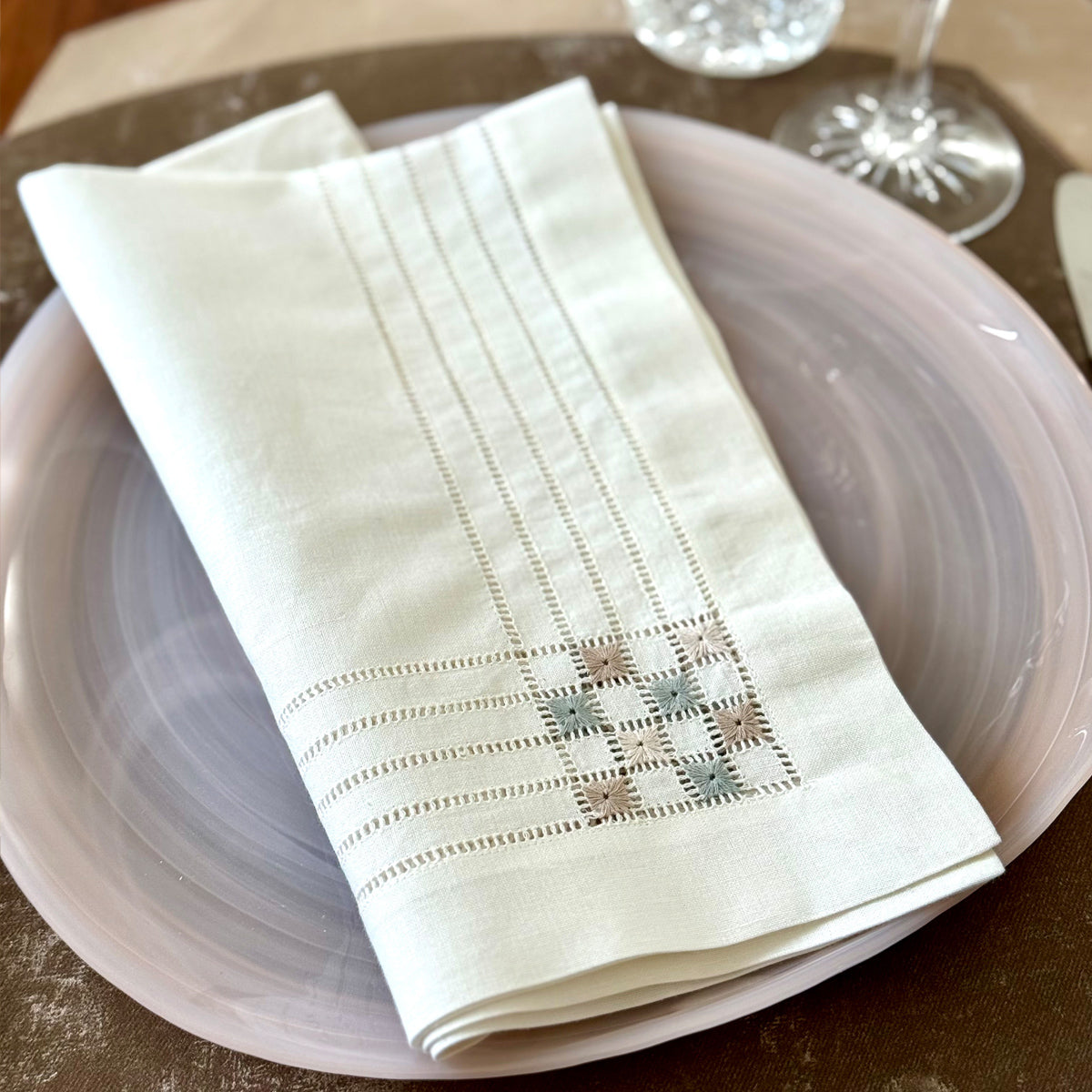 Hemstitched napkin featuring color blocked embroidery corners, with a vinyl placemat in the back that looks and feels like velvet.