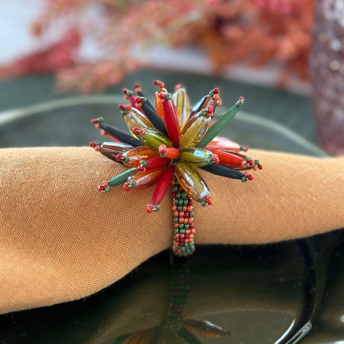 Close-up of a napkin ring adorned with beads in Fall/Autumn like colors, harvest inspired, on a mustard napkin. Thanksgiving vibes.