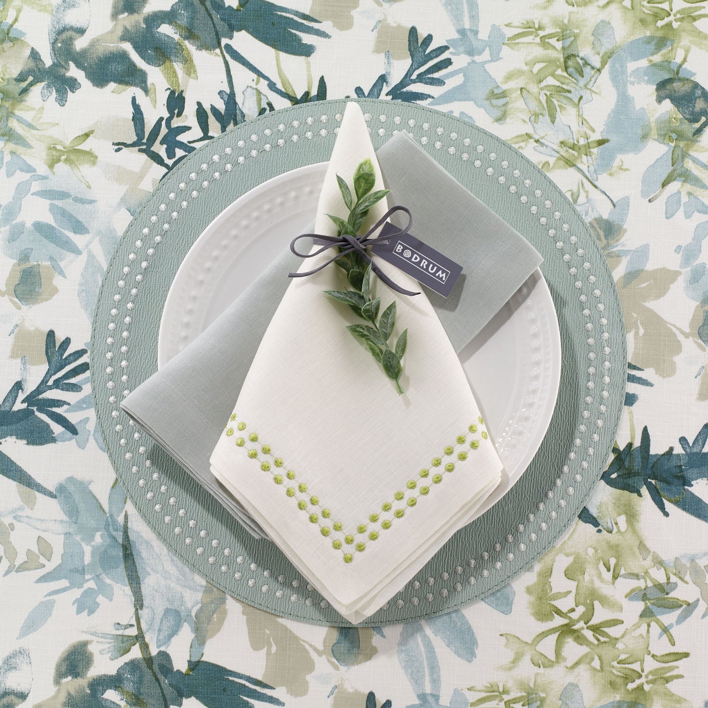Napkin with embroidered details resembling pearls with matching vinyl placemat under. Embroidered vinyl mat.
