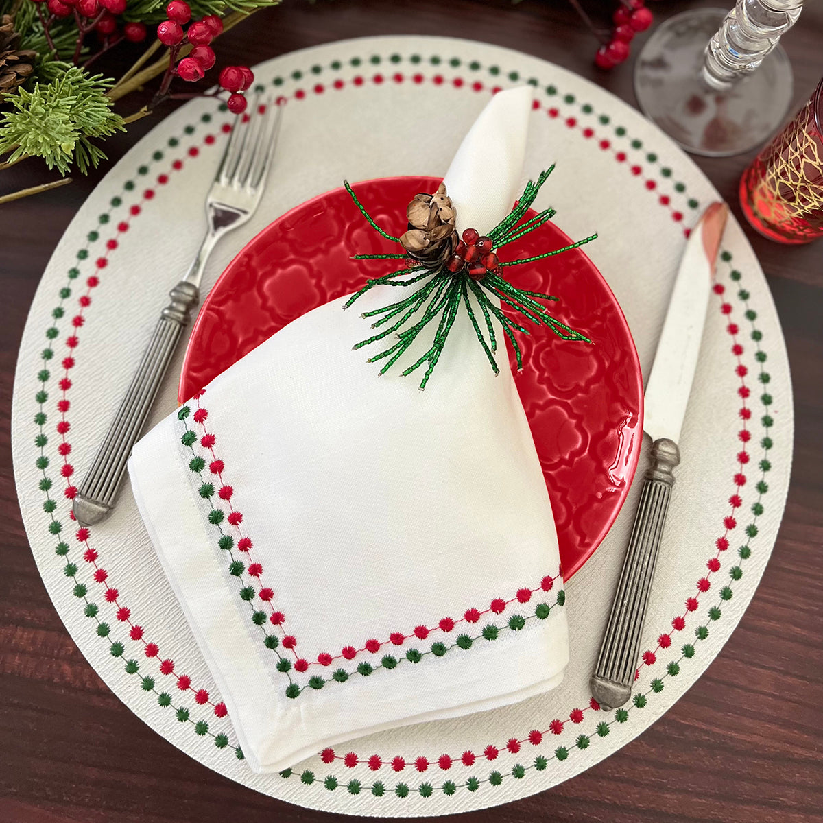Linen napkin with red and white embroidery detail resembling pearls. Matching vinyl placemat with the same embroidery detail. Christmas and holiday table.
