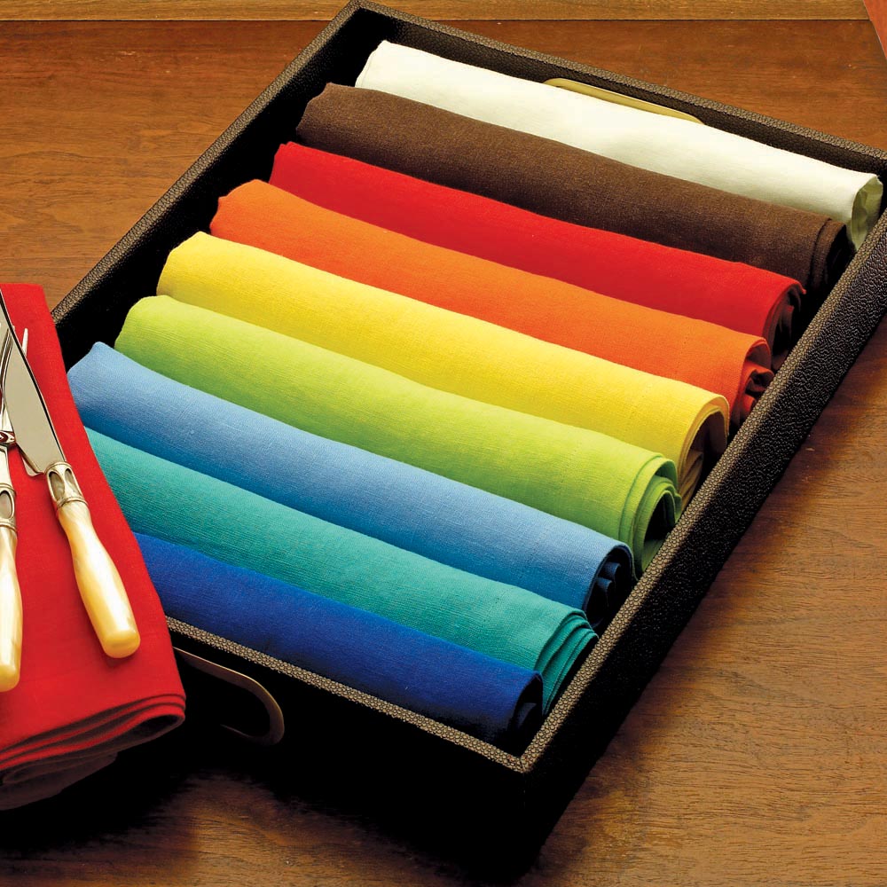 Stonewashed solid linen napkins rolled up in a tray presenting their variety of colors from neutral to colorful.