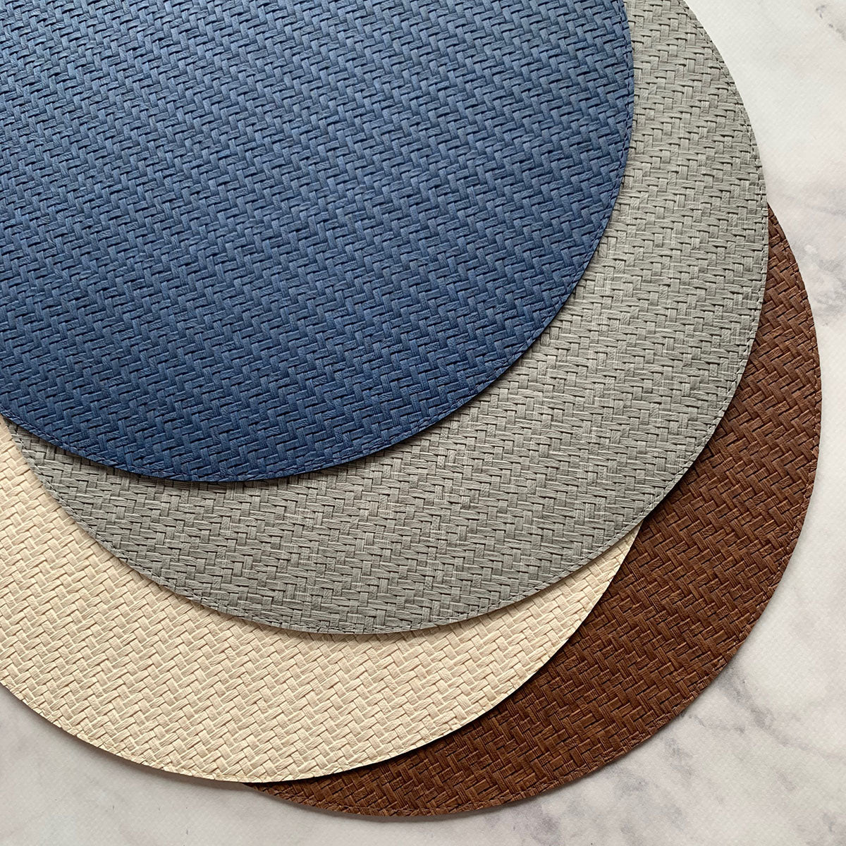 Round vinyl placemats with wicker like texture and design in Navy, Gray, Cream and chocolate