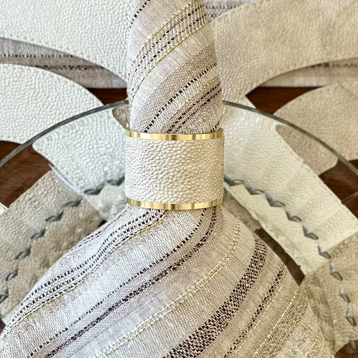 Close up a Pear colored vinyl napkin ring with gold edges on a beige napkin with metallic threads